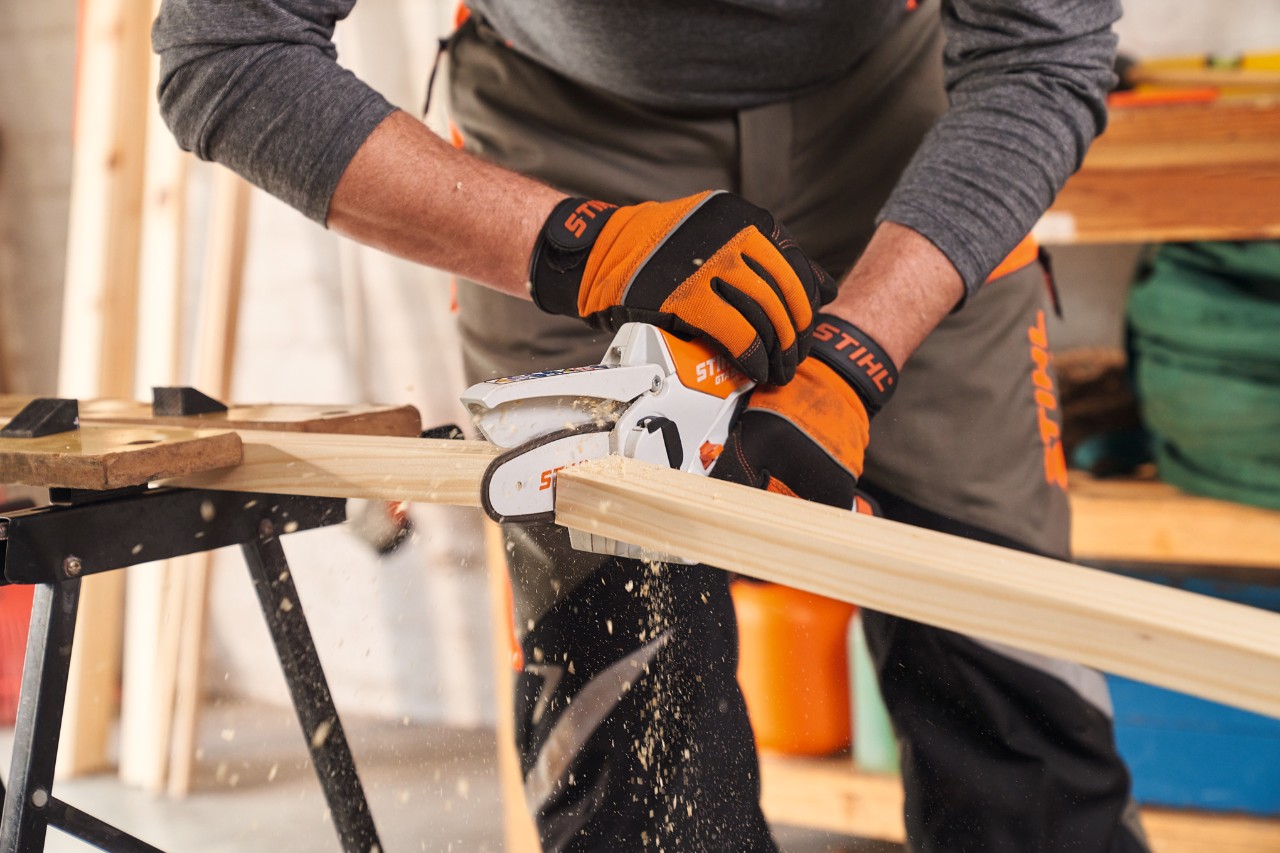 Човек с предпазни ръкавици STIHL Function Protect скъсява лайстните на рамката за визуална защита с резачка за клони STIHL GTA 26