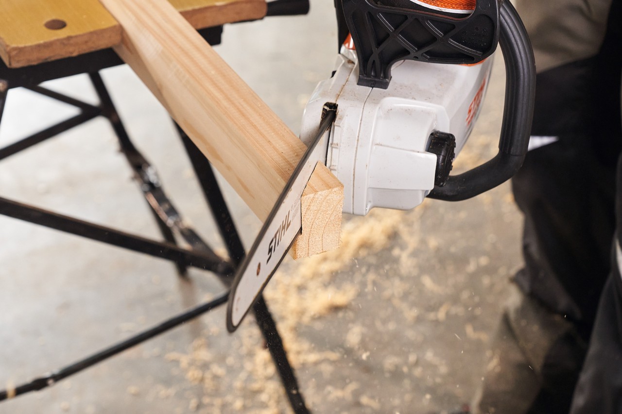 С акумулаторен моторен трион STIHL MSA 140 се отрязват до необходимата дължина квадратните профили дървен материал за стойките на ограда за визуална защита    