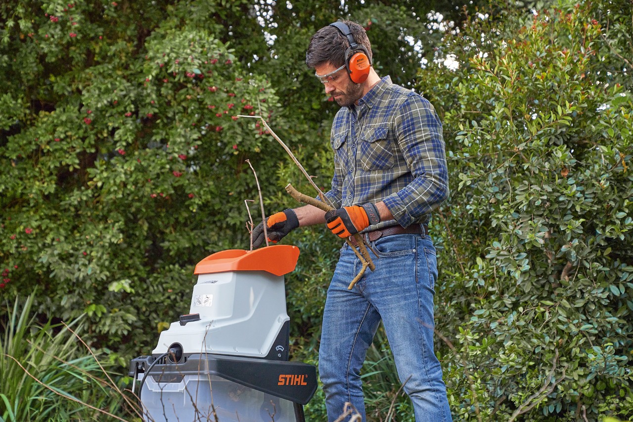 Мъж с предпазни средства раздробява клони с градинска дробилка STIHL  