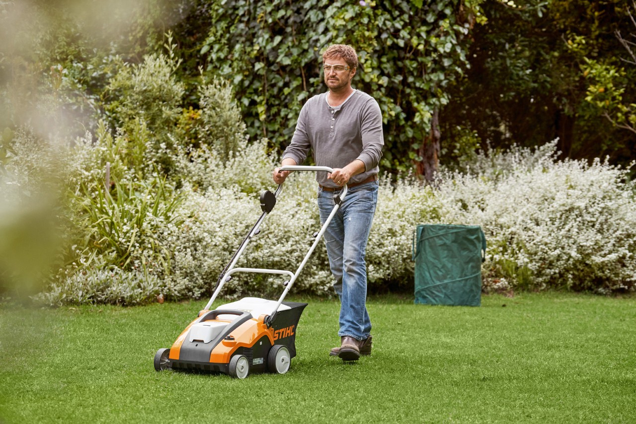 Мъж вертикутира зелена морава със STIHL акумулаторен аератор RLA 240