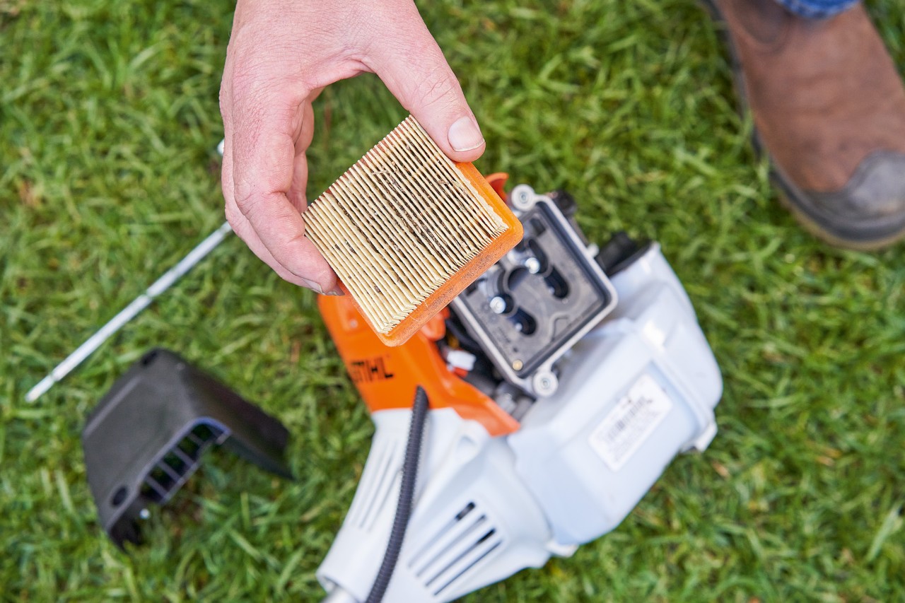 Човек взема въздушния филтър на моторна косачка STIHL, за да го почисти 
