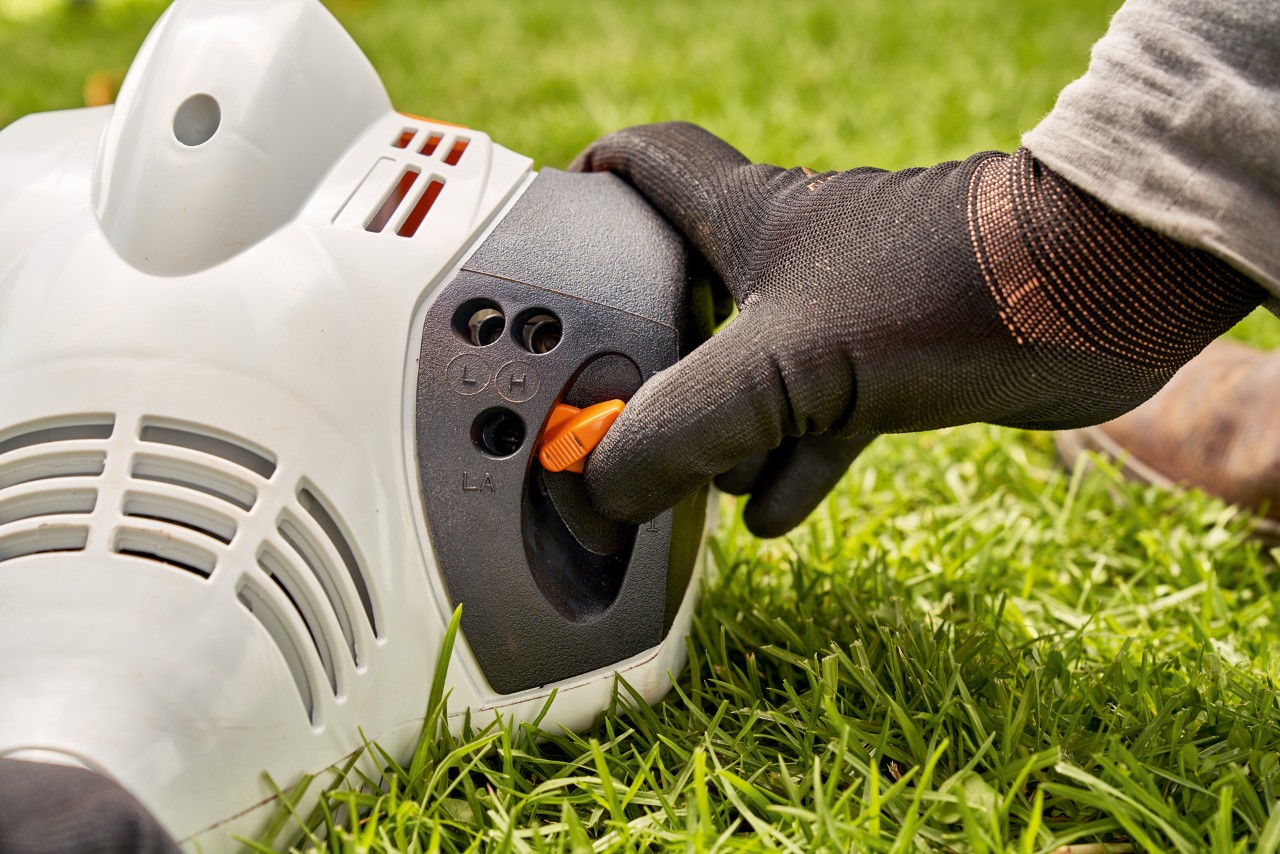 Мъж настройва лоста на бензиновата моторна косачка STIHL FS 56, за да я стартира