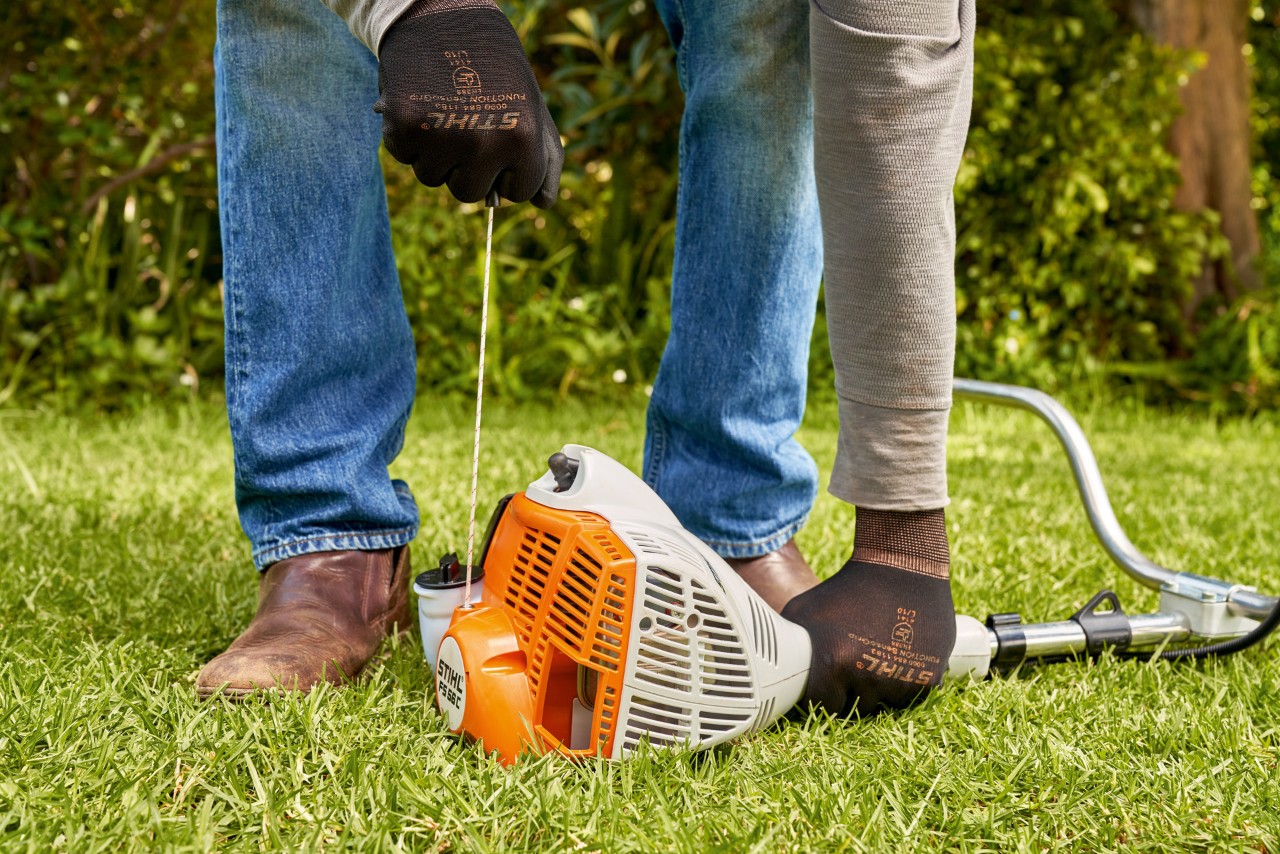 Мъж дърпа стартиращото въже на бензиновата моторна косачка STIHL FS 56 