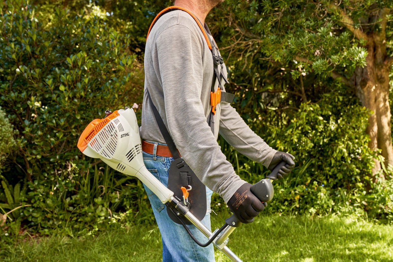 Мъж повдига бензиновата моторна косачка STIHL FS 56 от земята
