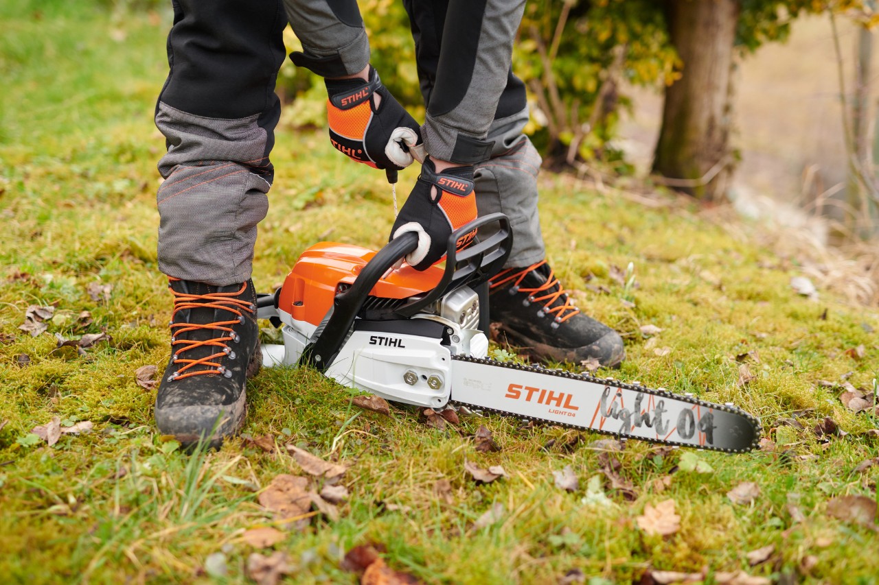 Верижният трион STIHL MS261CM е поставен на земята в гората, така че после да може да бъде стартиран безопасно от човека.