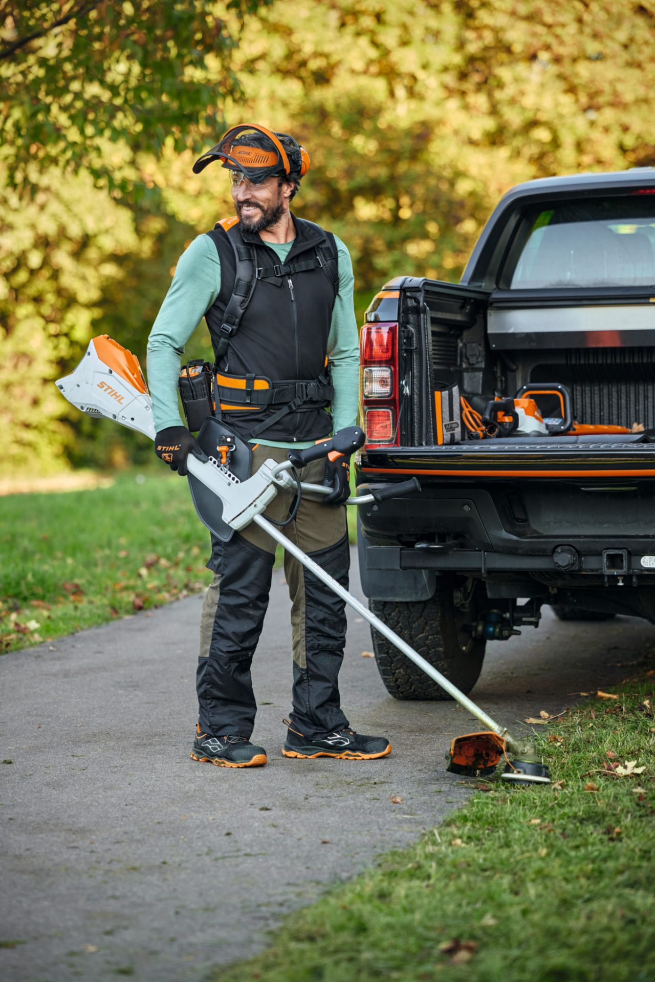 Мъж с FS комплект и акумулаторна коса STIHL FSA 200 пред автомобил