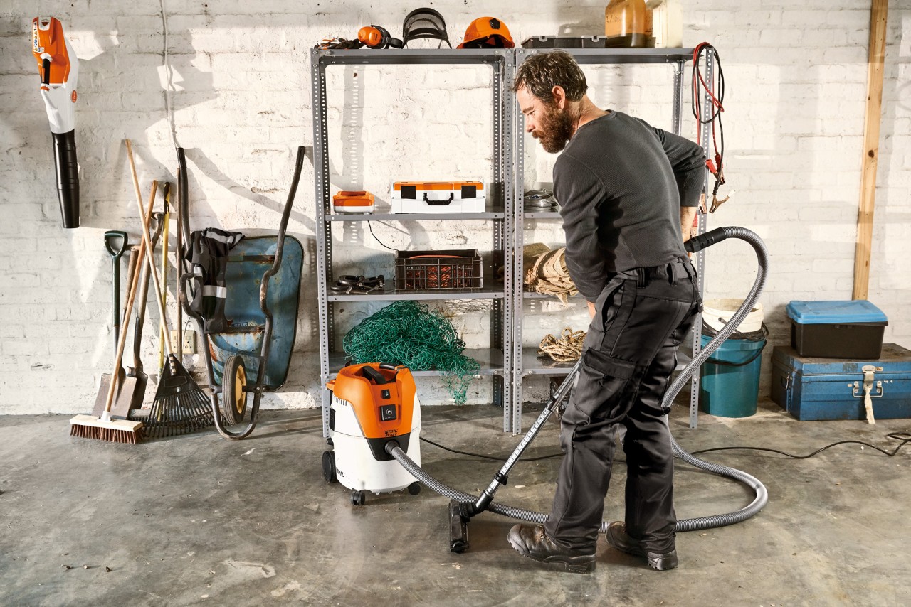Мъж почиства пода на гараж с прахосмукачка за сухо и мокро почистване STIHL SE 62 E