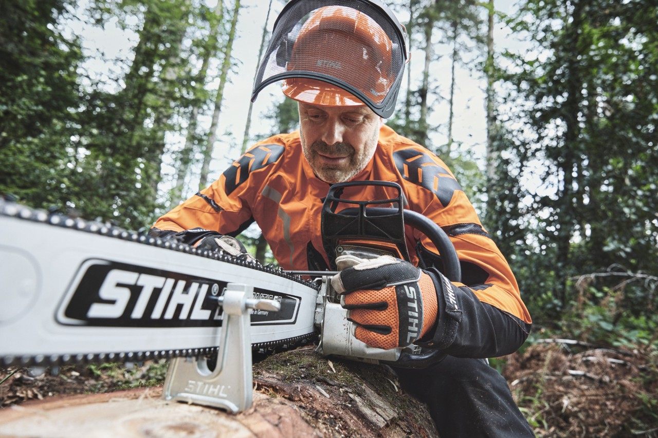 Мъж с лични предпазни средства работи с моторен трион STIHL в гората