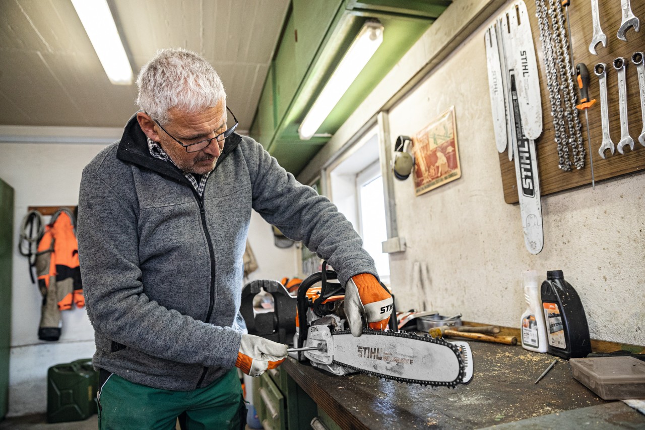 Мъж в сервиз монтира водеща шина STIHL Rollomatic E на моторен трион