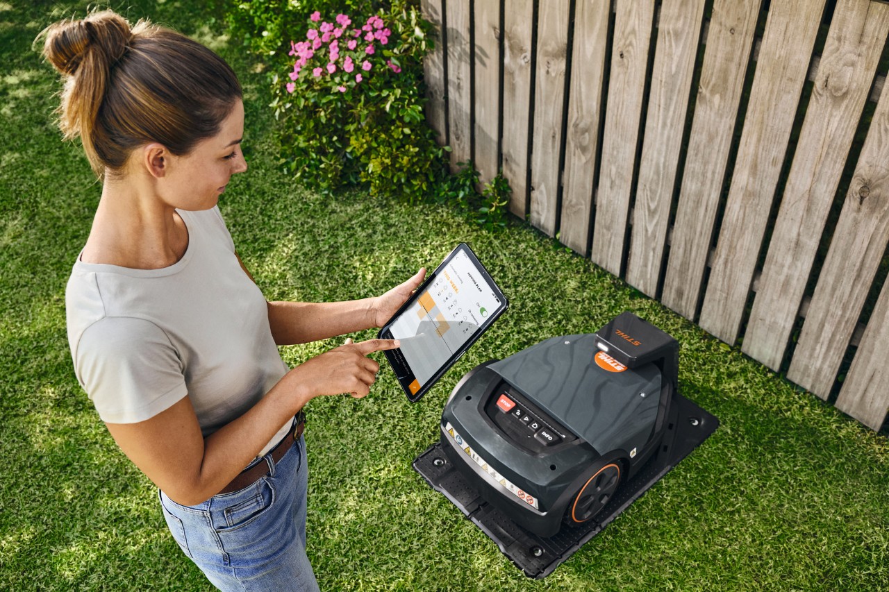 Жена управлява STIHL iMOW® EVO посредством таблет в своята градина