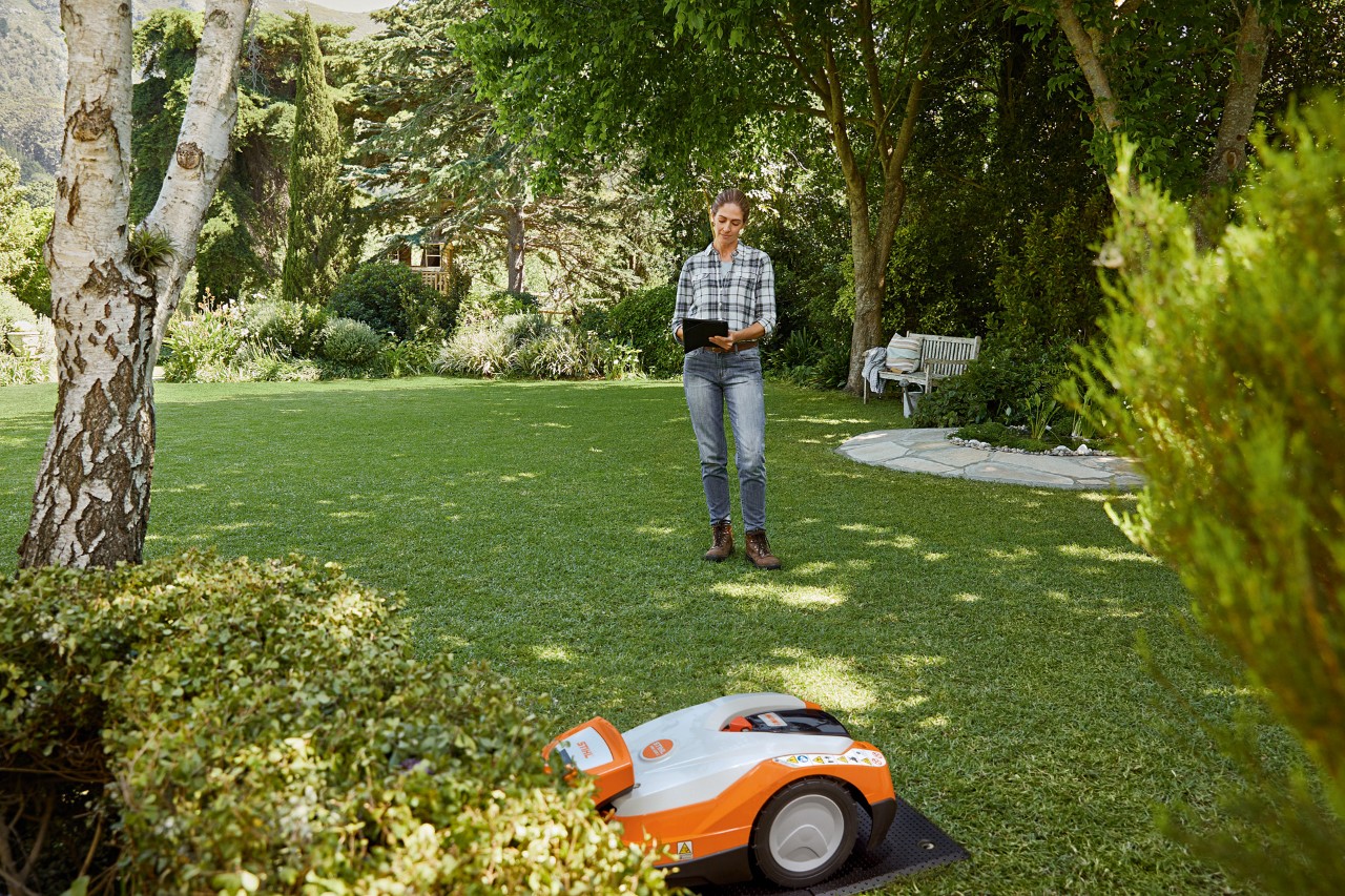 Жена управлява робота за косене STIHL iMOW® 522 чрез таблет