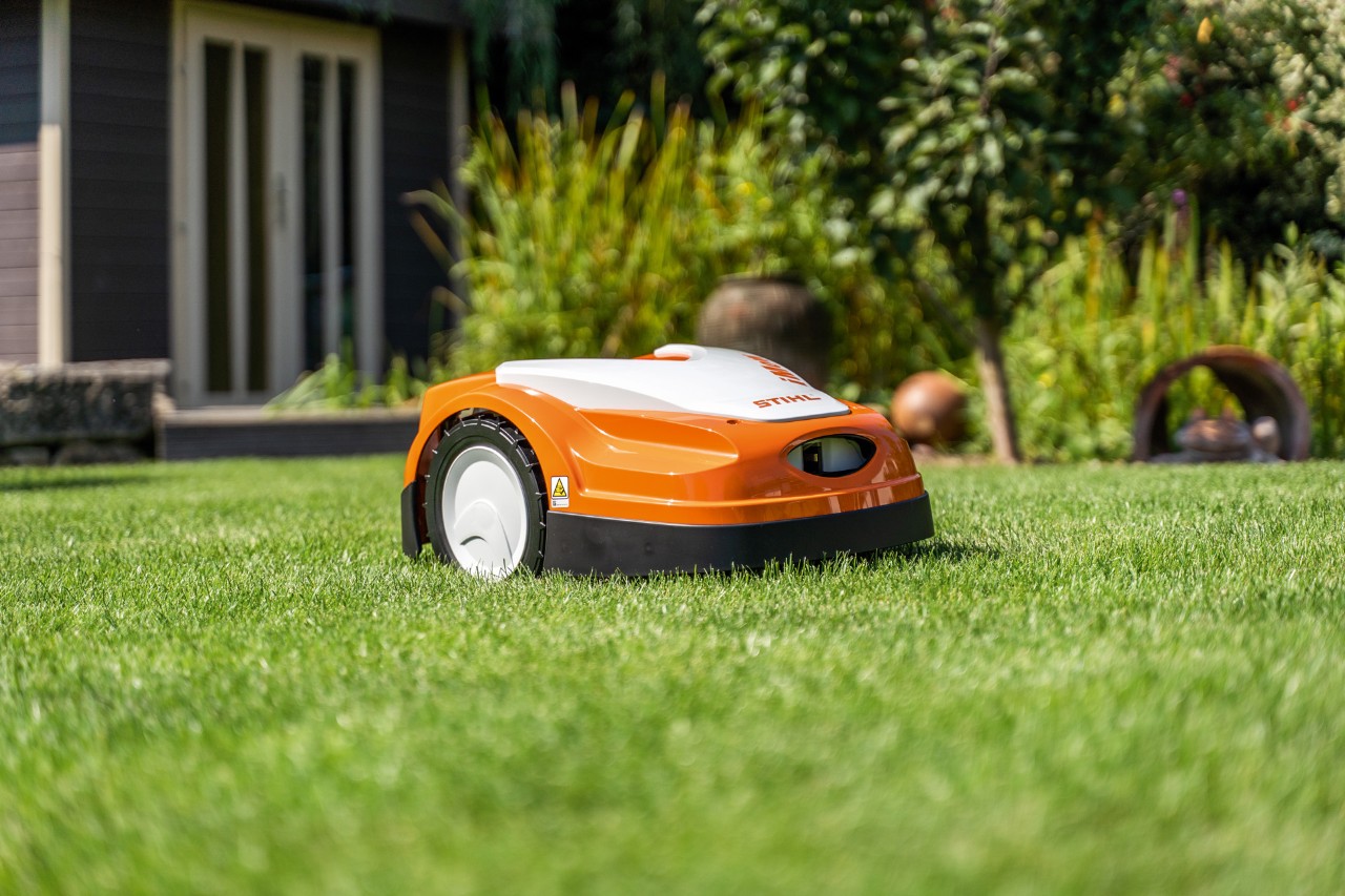 Косачка робот STIHL iMOW® RMI 422 върху зелена морава пред къща 