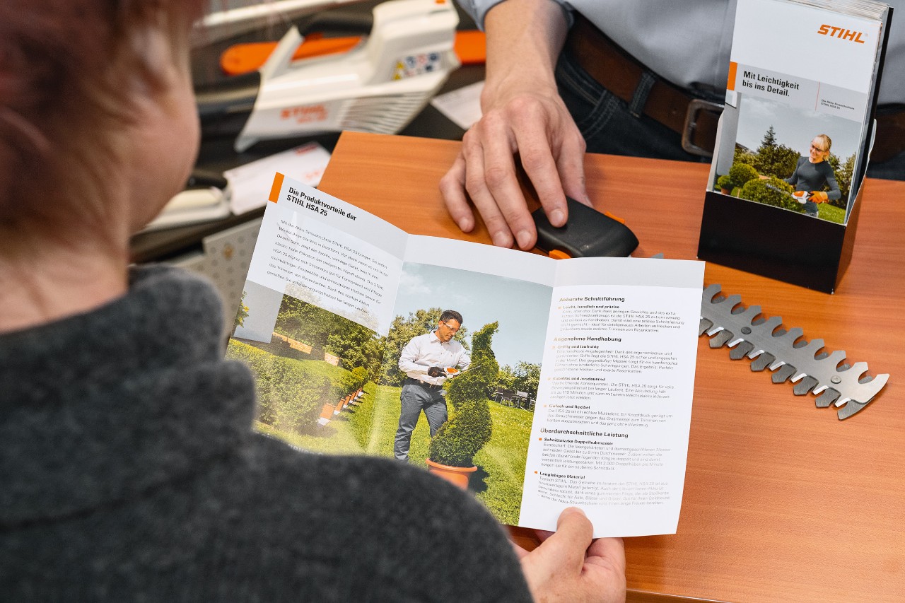Човек разглежда предимствата на продукта на STIHL HSA 25 в брошура